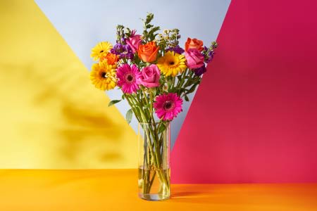 Bright flowers in a vase with a colourful background